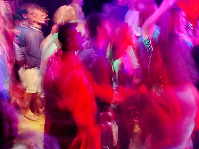 Rave dancers in natural motion - experimental digital photography by Rick Doble. Candid handheld photograph taken at 2 or 4 seconds (see EXIF data below) with an early digital camera in 2002 and shot under available light. Effects were created with photography and not created with computer graphics.