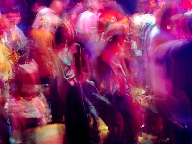 Rave dancers in natural motion - experimental digital photography by Rick Doble. Candid handheld photograph taken at 2 or 4 seconds (see EXIF data below) with an early digital camera in 2002 and shot under available light. Effects were created with photography and not created with computer graphics.